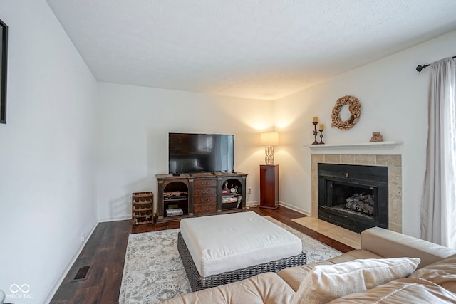 living area featuring baseboards, wood finished floors, and a tile fireplace