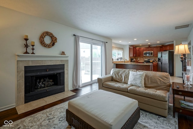 living room with a fireplace, light wood-style flooring, recessed lighting, baseboards, and visible vents