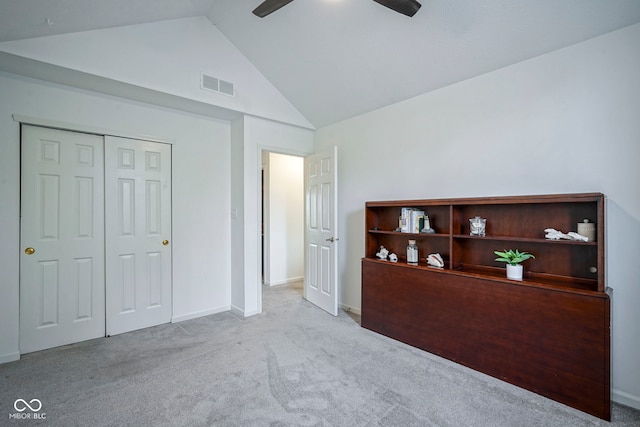 unfurnished bedroom featuring a ceiling fan, visible vents, vaulted ceiling, baseboards, and carpet flooring