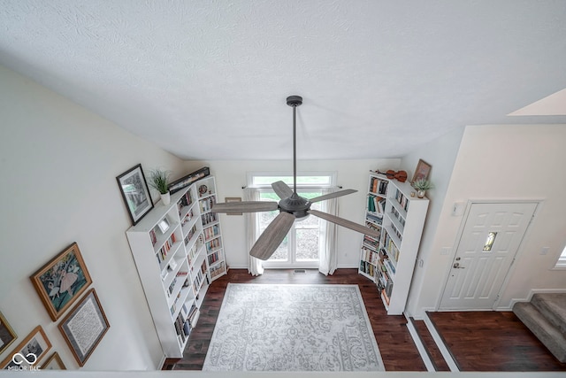 entrance foyer featuring a textured ceiling, ceiling fan, stairs, and wood finished floors