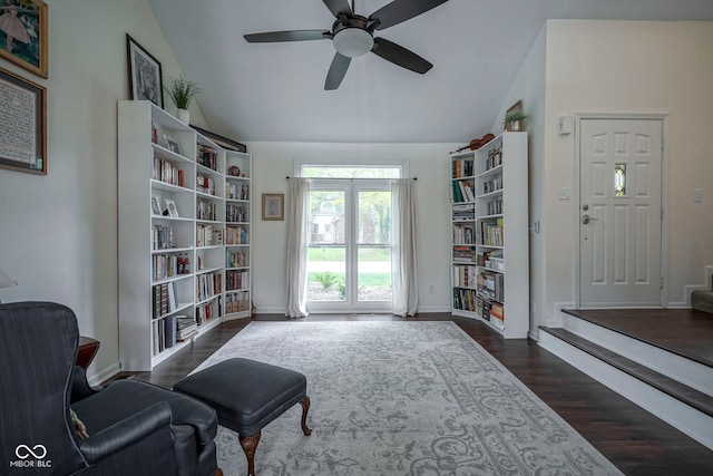 living area featuring baseboards, a ceiling fan, dark wood-style flooring, and vaulted ceiling