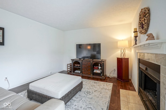 living room featuring baseboards, wood finished floors, and a tile fireplace