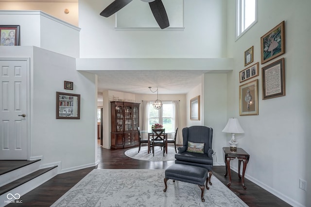living area featuring baseboards, a ceiling fan, and dark wood-style flooring