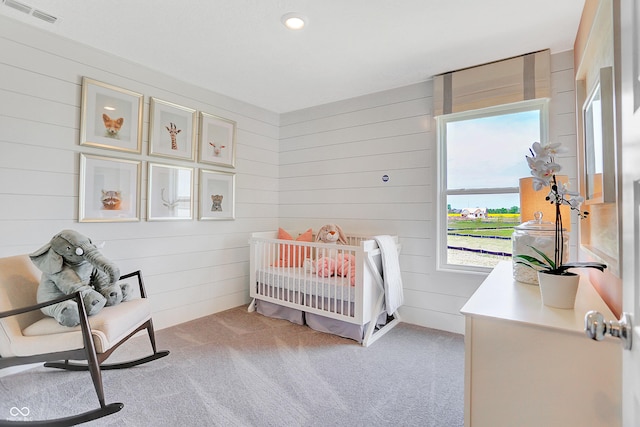 bedroom featuring wooden walls, visible vents, and light carpet