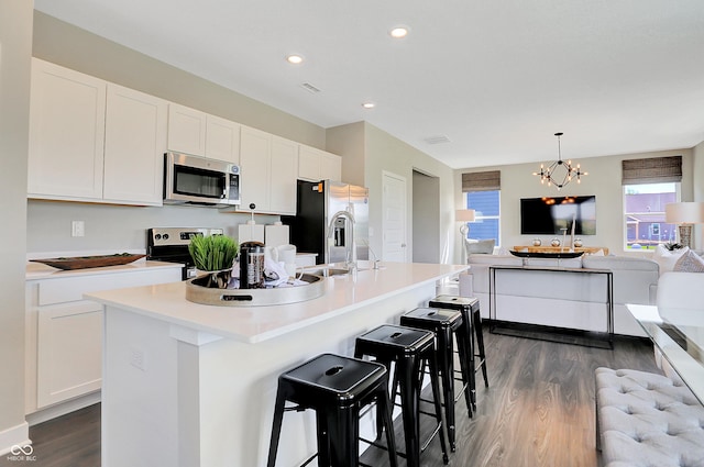 kitchen featuring an inviting chandelier, appliances with stainless steel finishes, dark wood-style floors, and white cabinetry