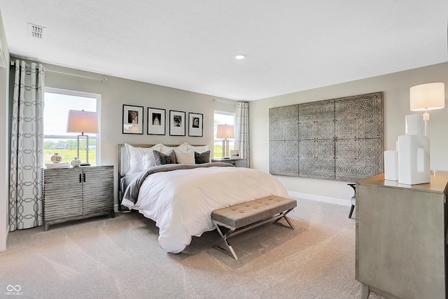 bedroom featuring baseboards, visible vents, light carpet, and multiple windows