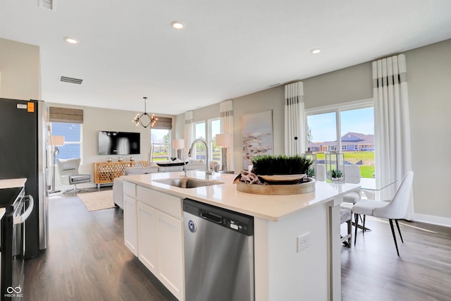 kitchen with appliances with stainless steel finishes, a healthy amount of sunlight, a sink, and dark wood-type flooring