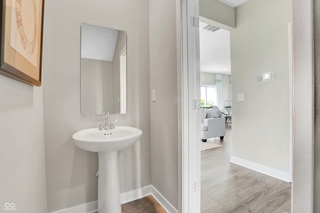 bathroom featuring a sink, baseboards, and wood finished floors