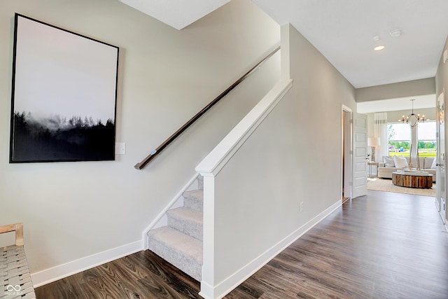 stairway with baseboards, recessed lighting, wood finished floors, and a notable chandelier