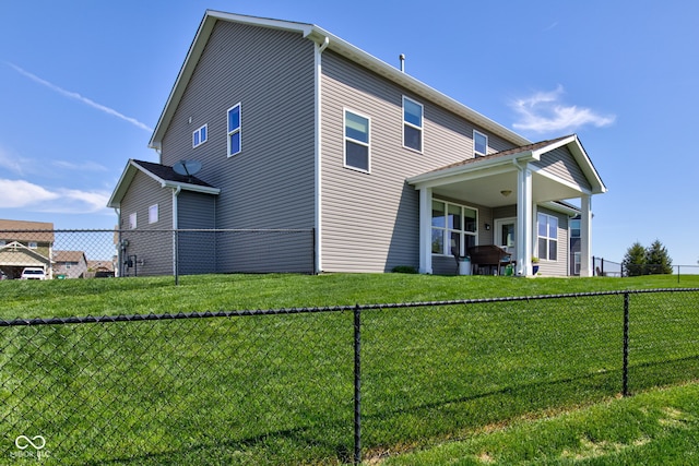 rear view of house with a lawn and a fenced backyard