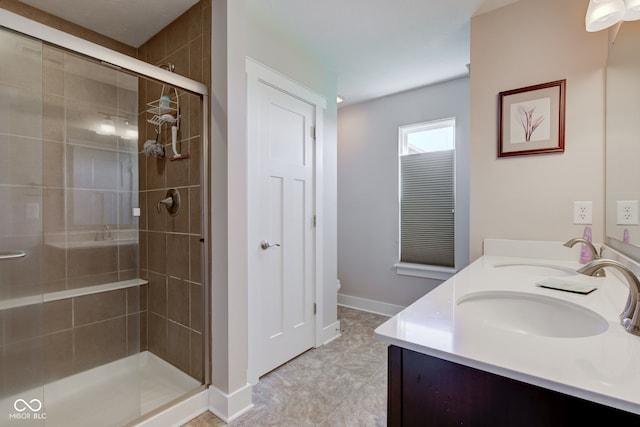 bathroom with double vanity, baseboards, a shower stall, and a sink