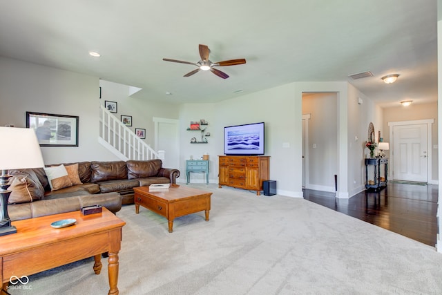 carpeted living room featuring stairs, a ceiling fan, baseboards, and visible vents