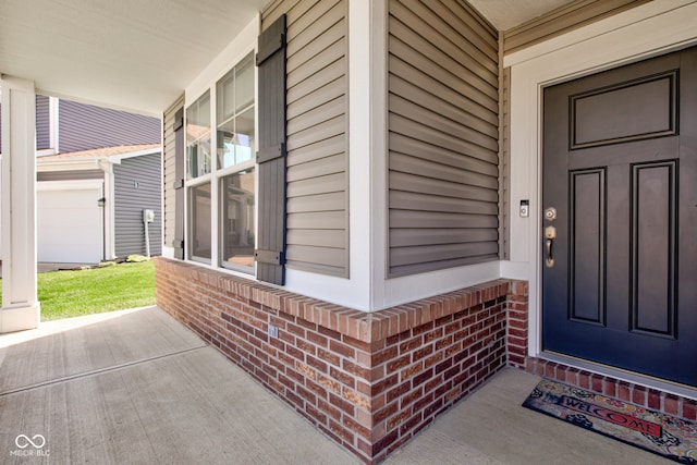 doorway to property featuring a porch and brick siding