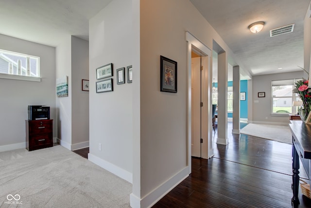 hallway with visible vents, baseboards, and wood finished floors