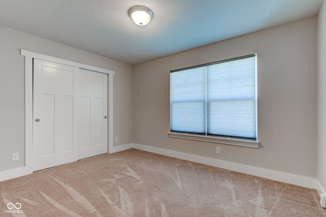unfurnished bedroom featuring baseboards, a closet, and carpet floors