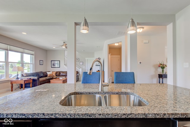 kitchen featuring a sink, light stone countertops, decorative light fixtures, and open floor plan
