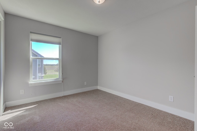 carpeted empty room featuring baseboards