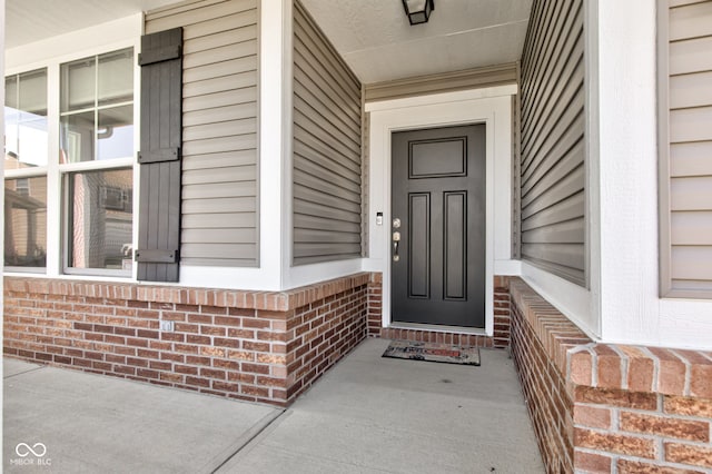 property entrance featuring brick siding and covered porch