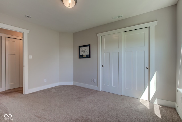 unfurnished bedroom featuring baseboards, carpet, a closet, and visible vents