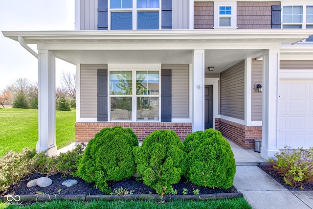 entrance to property with covered porch, brick siding, and a yard