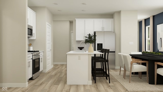kitchen featuring light wood-type flooring, a sink, white cabinets, a breakfast bar, and stainless steel appliances