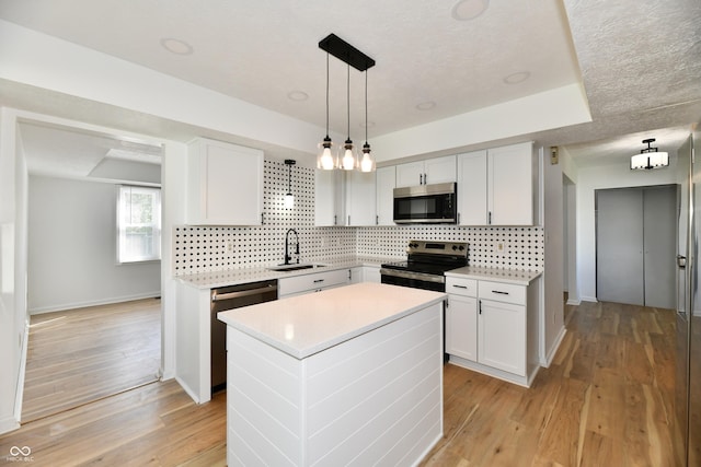 kitchen featuring a kitchen island, light countertops, tasteful backsplash, a sink, and appliances with stainless steel finishes