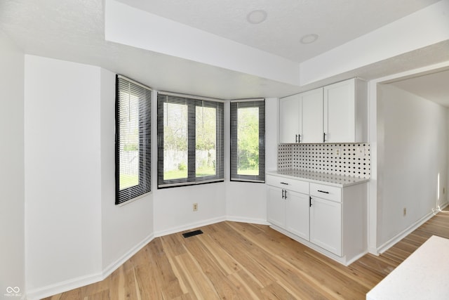 interior space featuring light countertops, baseboards, light wood-type flooring, and visible vents
