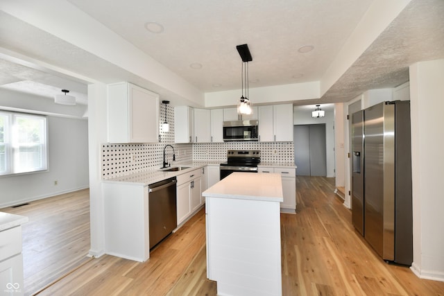 kitchen with appliances with stainless steel finishes, tasteful backsplash, a center island, a sink, and light countertops