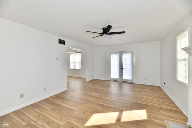 empty room featuring visible vents, a ceiling fan, a healthy amount of sunlight, and french doors
