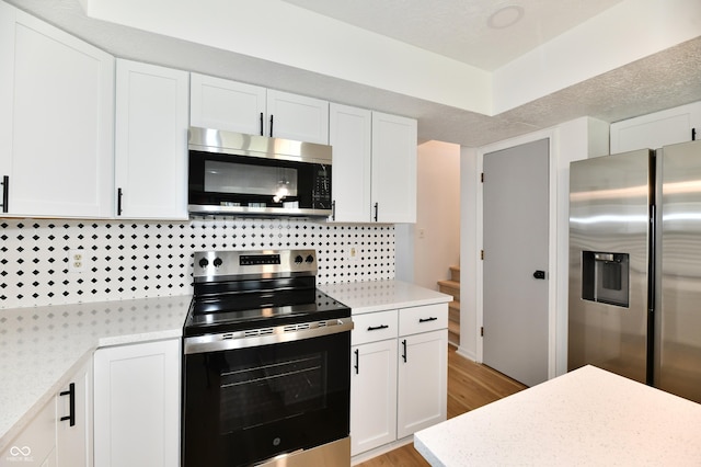 kitchen featuring light wood-style floors, white cabinetry, appliances with stainless steel finishes, and tasteful backsplash