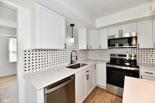 kitchen featuring stainless steel appliances, white cabinetry, a sink, and tasteful backsplash