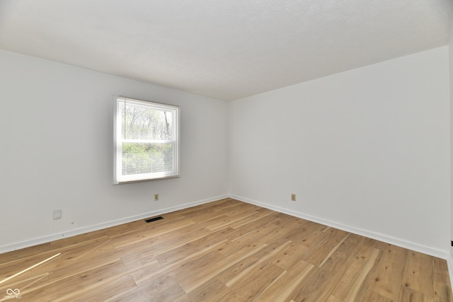 spare room with baseboards, visible vents, and light wood-style floors