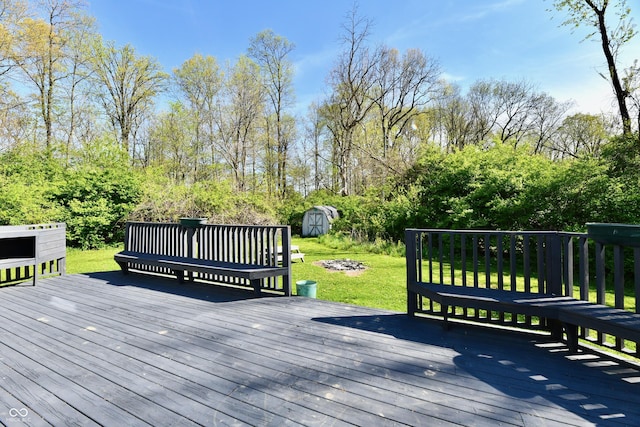 wooden deck with a storage unit, a lawn, and an outbuilding
