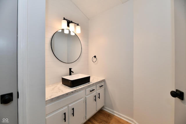 bathroom featuring vanity, lofted ceiling, wood finished floors, baseboards, and backsplash