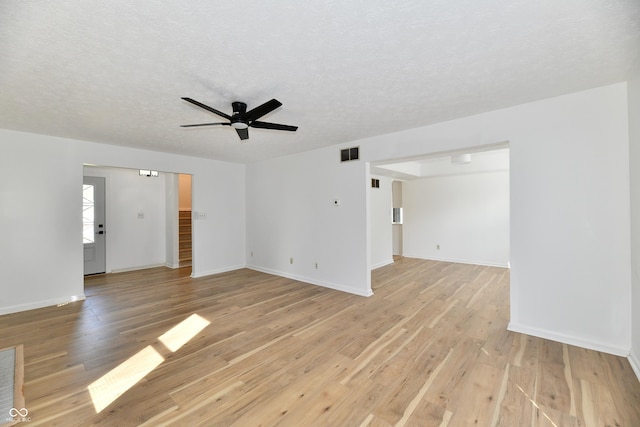 unfurnished living room featuring a textured ceiling, light wood-style flooring, a ceiling fan, baseboards, and visible vents