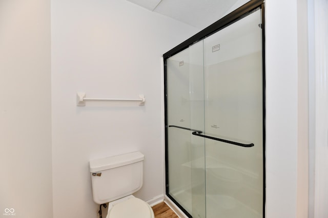 bathroom featuring wood finished floors, a stall shower, and toilet