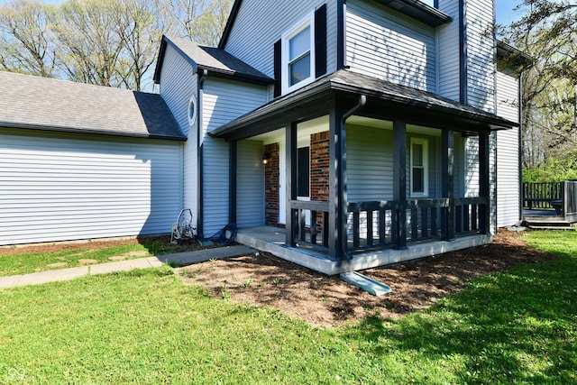 exterior space featuring a lawn, covered porch, a chimney, and roof with shingles