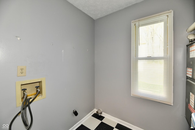 clothes washing area featuring washer hookup, laundry area, a textured ceiling, baseboards, and tile patterned floors