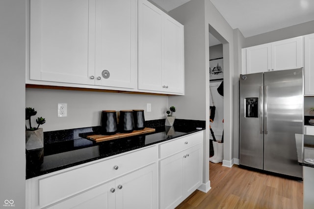 kitchen with light wood-style flooring, dark stone countertops, white cabinetry, baseboards, and stainless steel refrigerator with ice dispenser