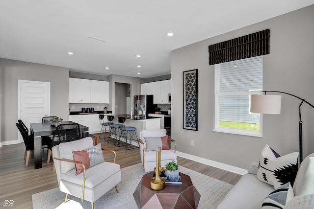 living area with recessed lighting, baseboards, and light wood finished floors