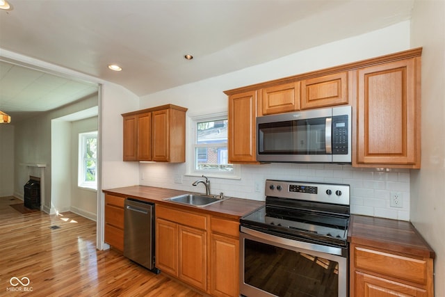 4710 Hinesley Ave, Indianapolis, IN 46208 - kitchen with brown cabinets, a sink, light wood-style flooring, appliances with stainless steel finishes, and backsplash