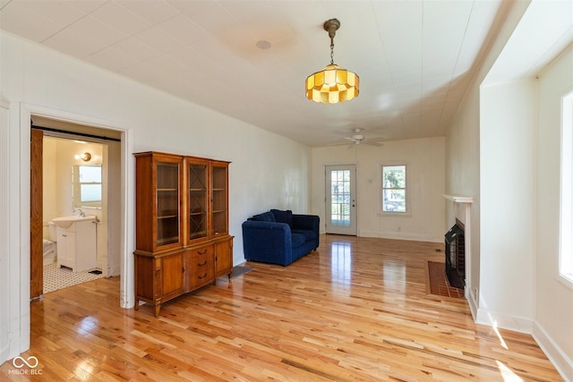 4710 Hinesley Ave, Indianapolis, IN 46208 - unfurnished room featuring light wood-type flooring, a ceiling fan, a fireplace with flush hearth, and a sink