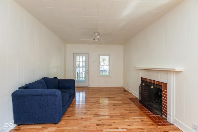 4710 Hinesley Ave, Indianapolis, IN 46208 - living room featuring light wood-style floors, a ceiling fan, wooden walls, and a fireplace