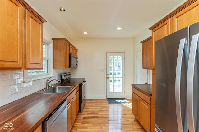 4710 Hinesley Ave, Indianapolis, IN 46208 - kitchen with wooden counters, tasteful backsplash, a sink, light wood-style flooring, and appliances with stainless steel finishes