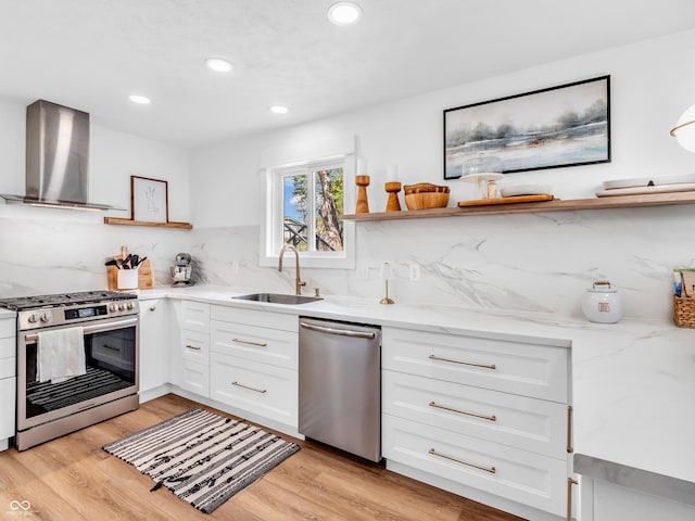 kitchen featuring wall chimney range hood, decorative backsplash, open shelves, a sink, and stainless steel appliances