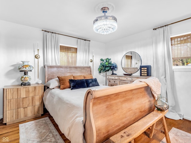 bedroom featuring baseboards, an inviting chandelier, and wood finished floors