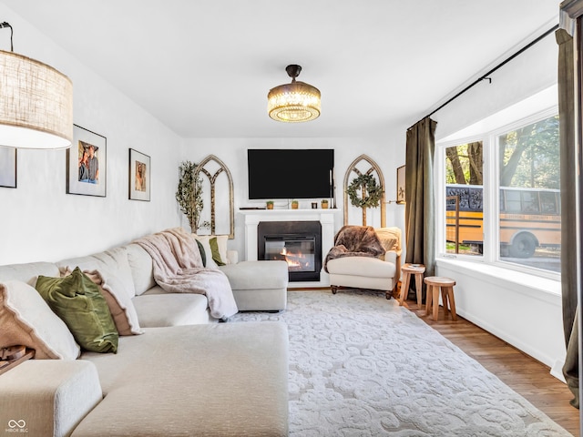 living room featuring baseboards, a glass covered fireplace, and wood finished floors
