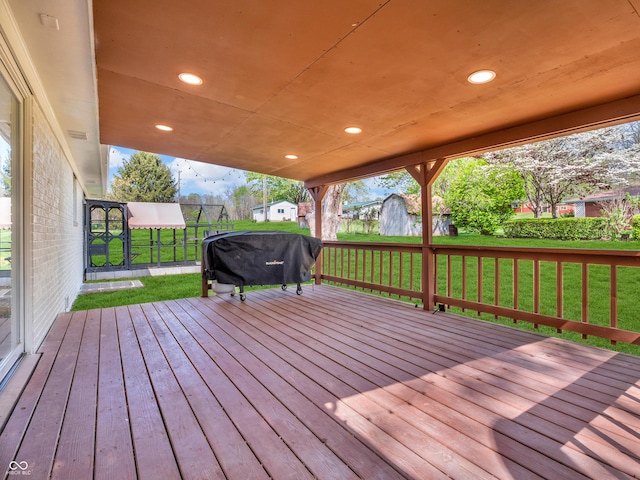 wooden terrace featuring a yard and a grill