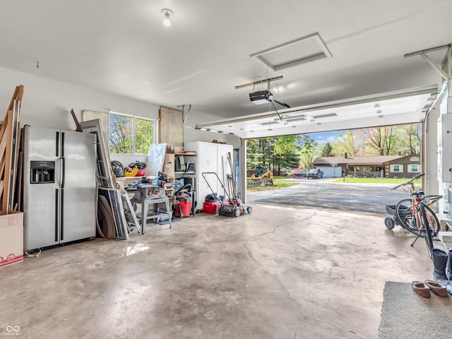 garage featuring stainless steel fridge with ice dispenser and a garage door opener