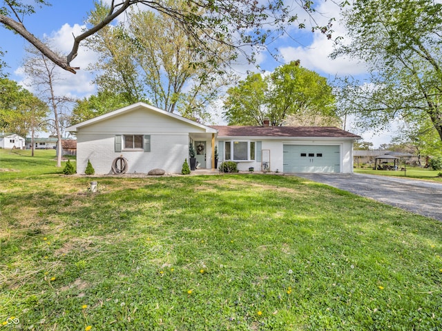 ranch-style home featuring a chimney, a front yard, brick siding, aphalt driveway, and an attached garage